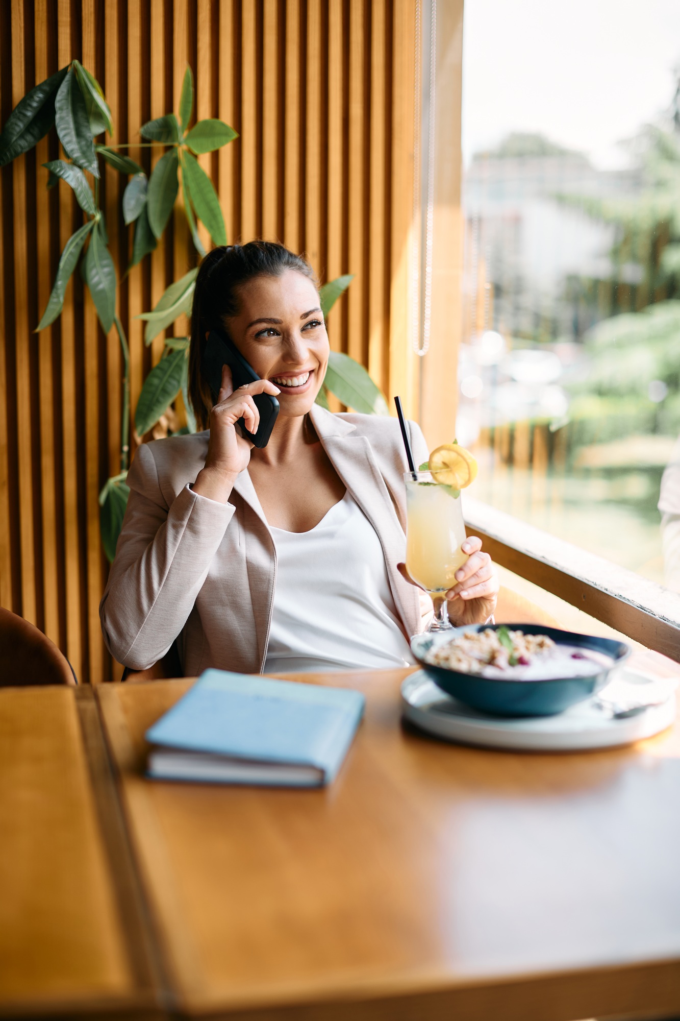 Young happy businesswoman making a phone call while relaxing in a cafe.