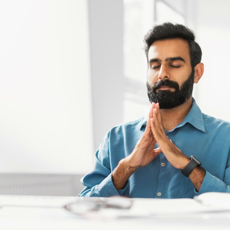 Serene indian businessman meditating for calmness in office