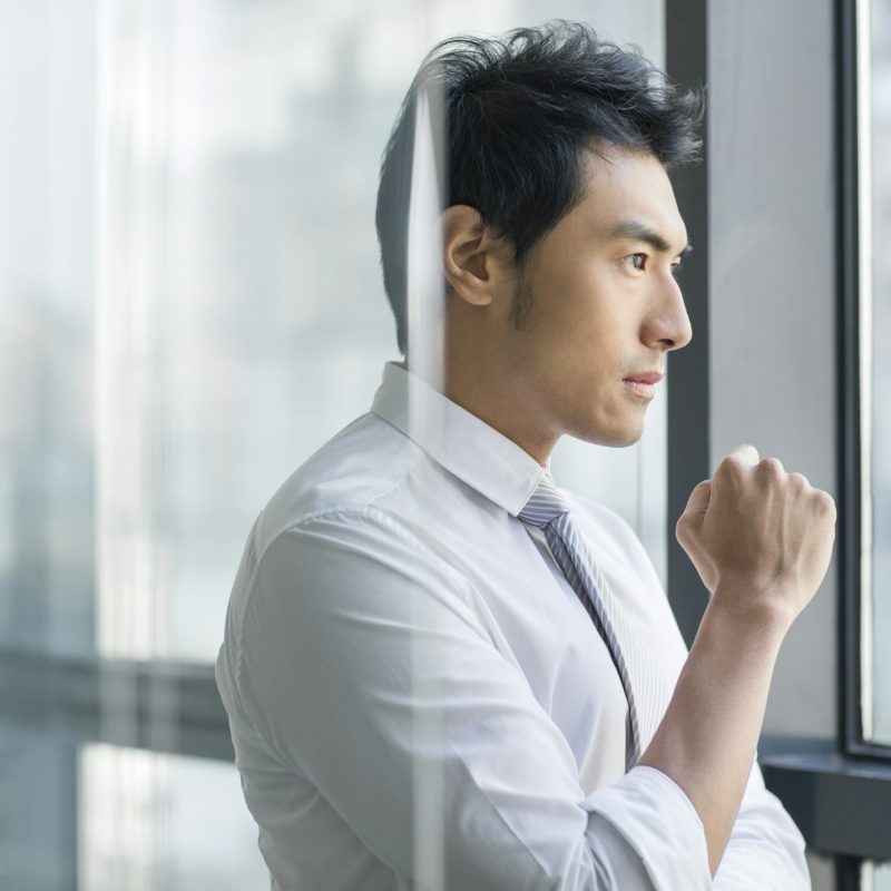 Young businessman looking through window